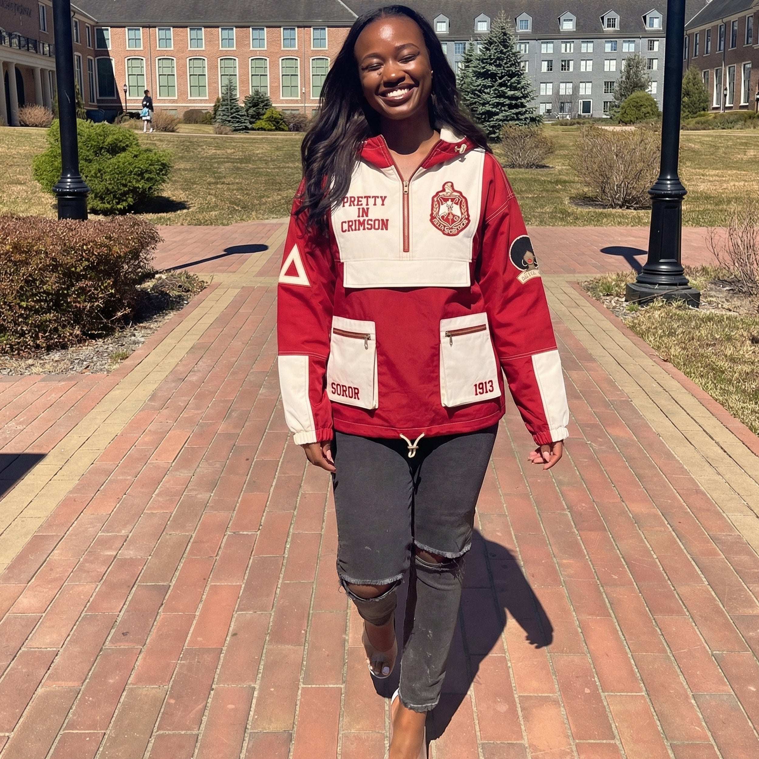 Person wearing a red and white jacket with a school logo on a brick path