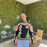 Woman wearing AKA Alpha Kappa Alpha black pink green racing panel sweatshirt with geometric colorblock design styled with jeans
