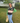 Woman wearing AKA Alpha Kappa Alpha black green rugby polo shirt with pink AKA stripe and ivy shoulder embroidery styled with jeans
