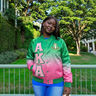 Person wearing a green and pink letterman jacket with 'A K A' on it, standing outdoors.